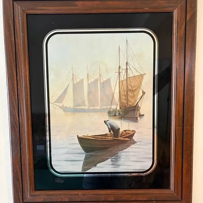 Framed vintage nautical print featuring sailboats and a fisherman in a rowboat, presented under glass with a black mat and wooden frame.
