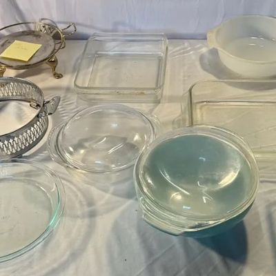 Collection of vintage glass kitchenware, featuring Pyrex baking dishes, white opal glass mixing bowls, clear pie plates, and metal...