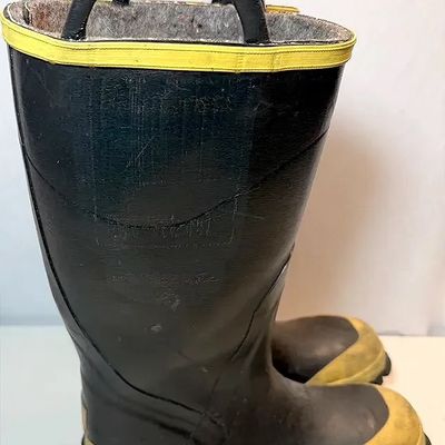 Pair of heavy-duty black rubber firefighter boots featuring pull-on handles, yellow trim, reinforced toes, and felt lining.