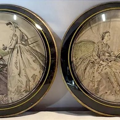 Pair of vintage round framed fashion prints under convex glass, featuring Victorian-era women in detailed gowns.