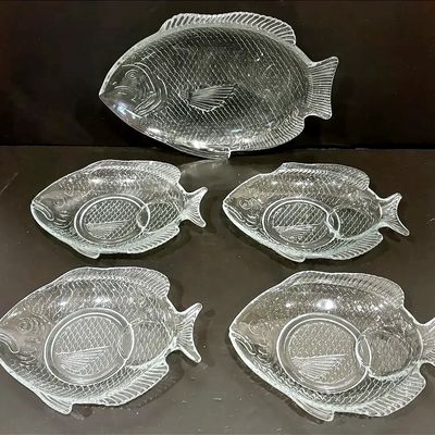 Vintage clear glass fish-shaped serving set featuring one large platter and four individual side dishes with detailed scale textures.