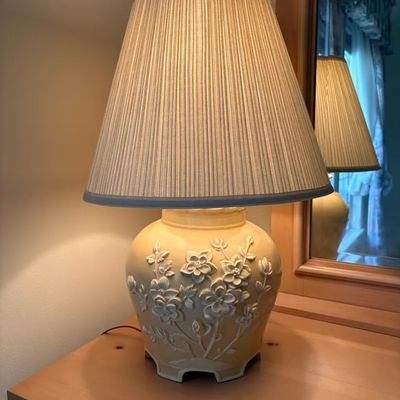 Vintage ceramic table lamp featuring a yellow ginger jar base with raised floral relief design and a pleated fabric lampshade.