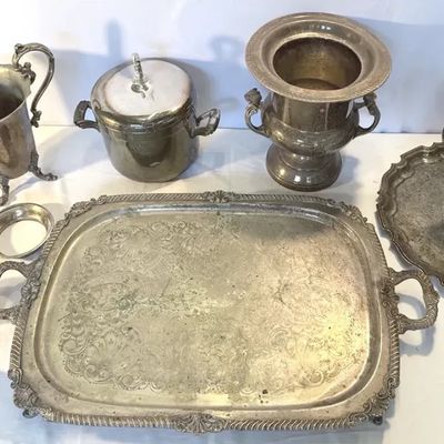 Assorted vintage silver-plated tea set items, serving trays, ice bucket, and urn showing natural tarnishing and patina.