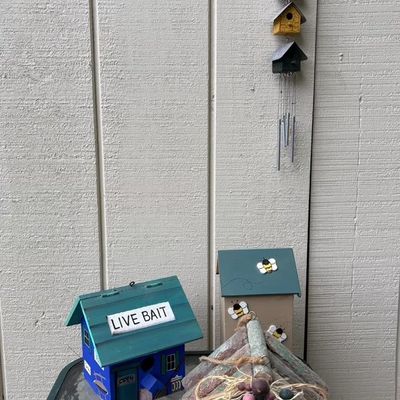 Collection of decorative wooden birdhouses and a hanging birdhouse wind chime, featuring a rustic twig house and themed painted designs.