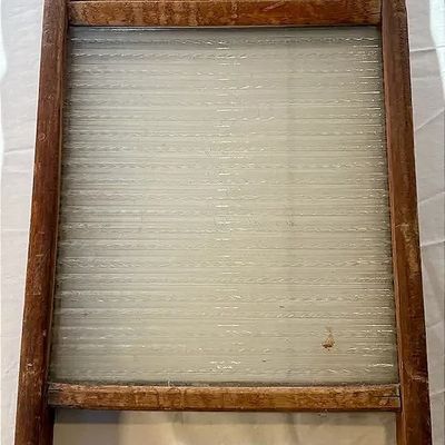Vintage glass and wooden washboard showing rustic wear and an intact ribbed glass insert.