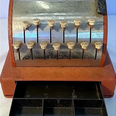 Vintage painted metal toy cash register featuring a working push-key mechanism and pop-out cash drawer.