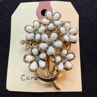 Vintage Coro floral bouquet brooch featuring white cabochon petals and rhinestone centers set in gold-tone metal.