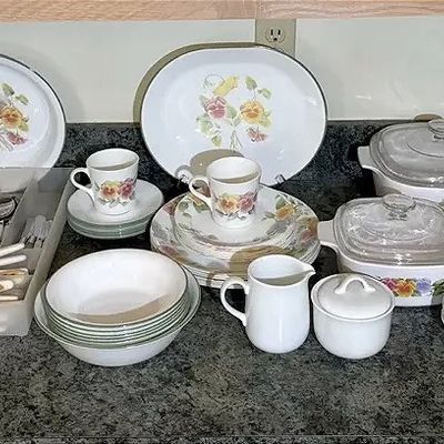 Corelle-style floral dinnerware set including plates, bowls, teacups, serving platters, and covered casserole dishes, accompanied by...