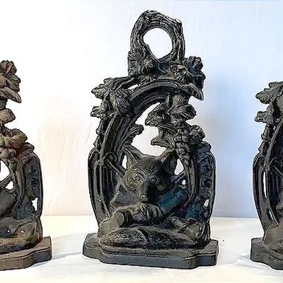 Set of three vintage cast iron fox doorstops or bookends featuring intricate foliage and rustic detailing.