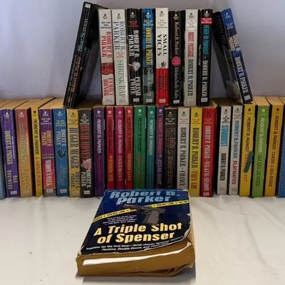 Large collection of paperback mystery novels by author Robert B. Parker, including a Spenser anthology in front.