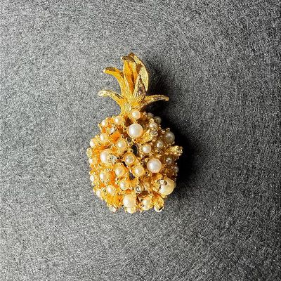 Vintage gold-tone pineapple brooch encrusted with imitation pearls and rhinestone accents.