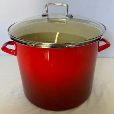 Red enameled steel stockpot with side handles and a clear glass lid.