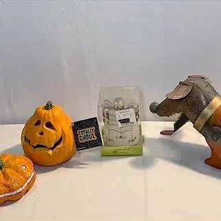 Collection of Halloween decor including a painted tin haunted house, Jack-o'-lantern figures, and a dachshund metal sculpture.