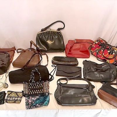 Large collection of women's handbags, purses, and clutches in various colors, materials, and styles displayed on a white surface.