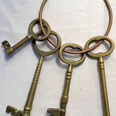 Set of four vintage brass decorative skeleton keys on a large copper-toned metal ring.