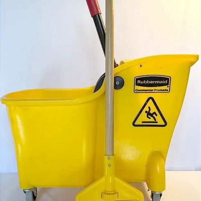 Rubbermaid Commercial yellow mop bucket with wringer and caster wheels, paired with a wooden mop handle.