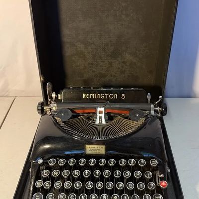 Vintage Remington 5 portable typewriter in black gloss finish, housed inside its original hard carrying case.