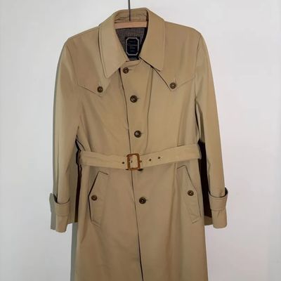 Vintage Christian Dior tan trench coat with a matching waist belt and classic buttoned lapel details.