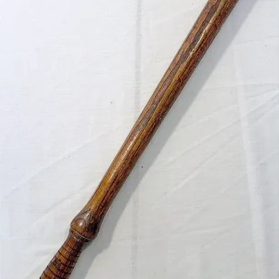 Vintage wooden nightstick baton featuring a carved ribbed grip and pommel end.