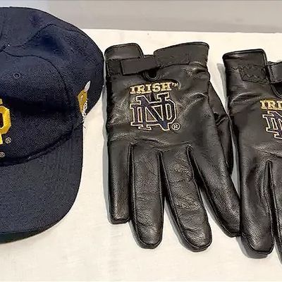 University of Notre Dame Fighting Irish baseball cap alongside a pair of black leather gloves with embroidered logos.