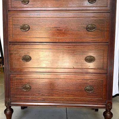 Traditional mahogany four-drawer chest with fluted side columns, turned legs, and brass hardware.