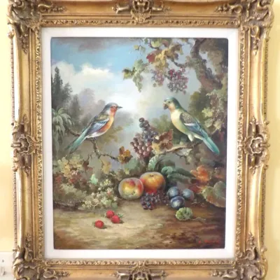 Framed still life oil painting depicting two songbirds perched among grapes, apples, and berries, set in an ornate gilded baroque-style...