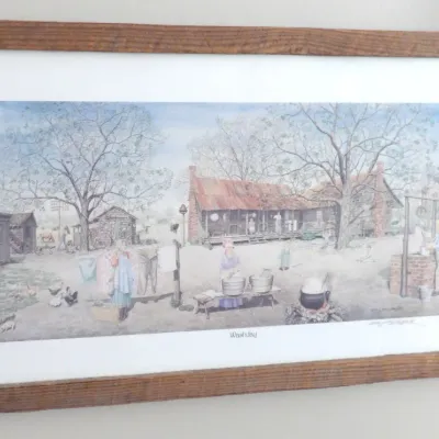 Framed art print titled "Washday" depicting a rustic rural homestead scene in a natural wood frame with white matting.