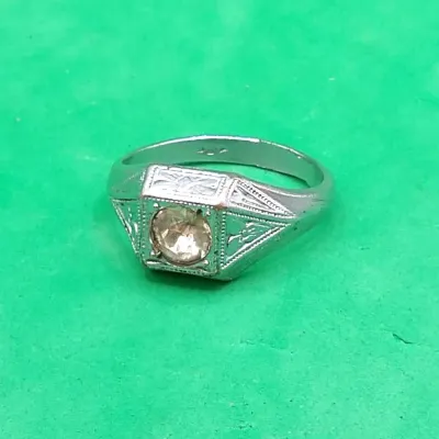 Vintage Art Deco style silver-tone signet ring featuring geometric filigree engraving and a central round clear stone set in a square bezel.