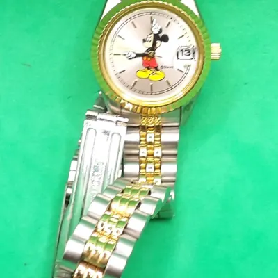 Disney Lorus Mickey Mouse two-tone wristwatch featuring a fluted bezel, silver-tone dial with Mickey character hands, and a date window.