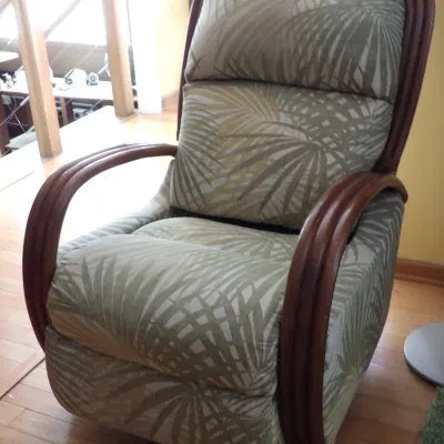 Rattan-frame reclining armchair featuring green tropical palm leaf upholstery.