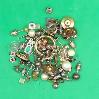Assorted pile of unbranded costume jewelry and findings, including faux pearl studs, earring backs, small hoops, and pendants.