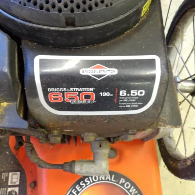 Briggs & Stratton 650 Series 190cc engine on a lawn mower, showing light wear and surface rust.