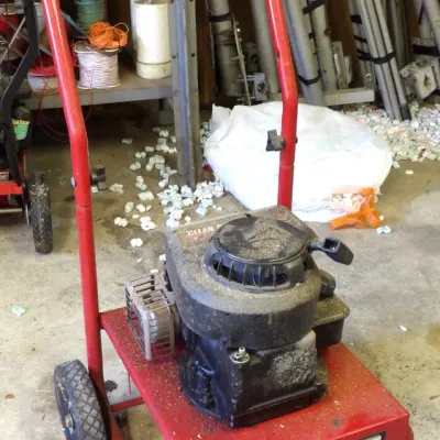 Generac gas-powered pressure washer unit on a red tubular steel cart, showing moderate wear and dust from use.