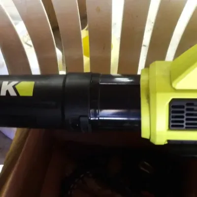IEWORK cordless electric leaf blower with battery attached, resting on a plastic chair.