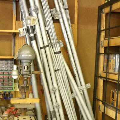 Vintage Delta Homecraft benchtop drill press standing alongside a large collection of disassembled aluminum ham radio antenna mast...