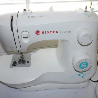 White Singer Simple portable sewing machine, featuring stitch length and pattern selector dials, appearing in clean, gently used condition.