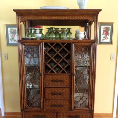 Tropical-style woven wicker and faux-bamboo hutch features glass-front cabinets with decorative scrollwork, built-in wine rack cubbies,...