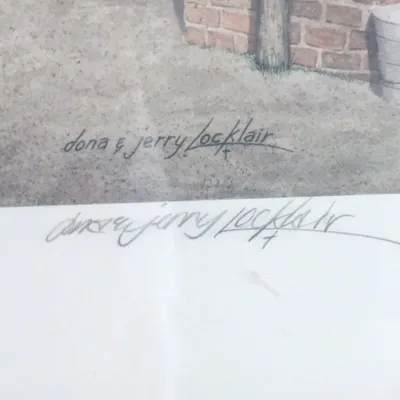 Detail shot of an artwork signature by artists Dona and Jerry Locklair, showing both the printed signature on the piece and a hand-signed...