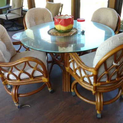 Vintage bentwood rattan dining set featuring a round glass-top pedestal table and four matching swivel armchairs on casters with tufted...