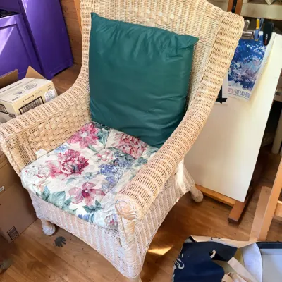 Natural wicker high-back armchair featuring a floral upholstered seat cushion and an accent green back pillow.