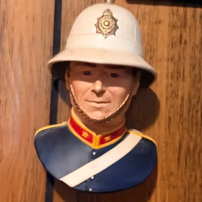 Vintage chalkware or ceramic wall pocket bust depicting a British bobby or police officer in full uniform with pith helmet.