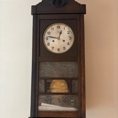 Sale Photo Thumbnail #189: Vintage dark oak pendulum wall clock with a brass pendulum and textured glass door inserts.