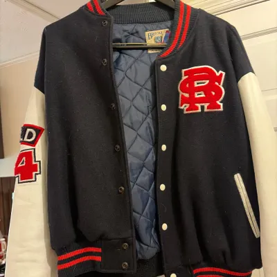 Vintage Brockum varsity jacket featuring a navy wool body, cream leather sleeves, red chenille letter patches, and a quilted lining.