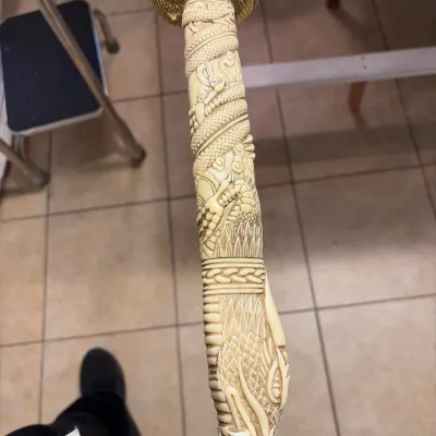 Intricately carved sword hilt featuring a dragon motif and a gold-toned tsuba guard.