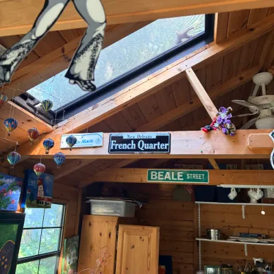 Collection of decorative street signs, novelty wall hanging cutouts, and small hot air balloon ornaments inside a wooden shed.
