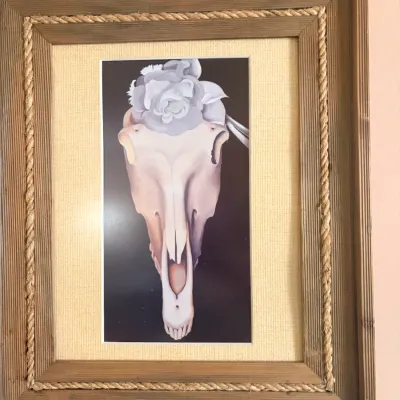 Framed print featuring a Georgia O'Keeffe style skull and flower composition, housed in a rustic wooden frame with rope trim detail.