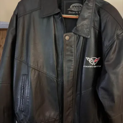 Black leather Corvette bomber jacket featuring an embroidered C5 crossed-flags logo on the chest and a zip-front closure.