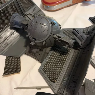 Vintage Star Wars Kenner TIE Interceptor vehicle toy, showing wear and detached solar panel sticker, alongside a Landspeeder toy.