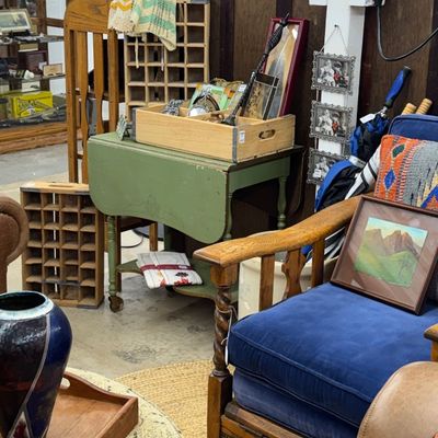 Sale Photo Thumbnail #33: Eclectic furniture showroom featuring an oak armchair with blue velvet cushions, a green drop-leaf table with casters, and various vintage home decor items.