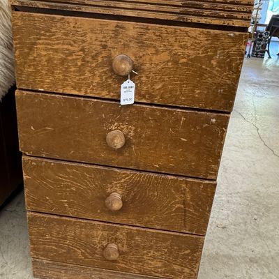 Rustic antique four-drawer wooden chest with round wooden knobs, showing a distressed, weathered finish.